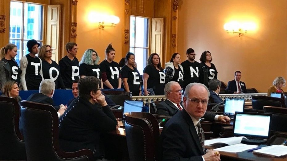 Protesters with shirts saying "Stop the Bans" gathered in the Ohio Senate chamber after legislators passed a bill banning abortions based on a Down syndrome diagnosis.