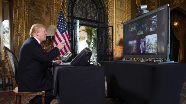 President Donald Trump points to the video screen during a Christmas Eve video teleconference with members of the mIlitary at his Mar-a-Lago estate in Palm Beach, Fla., Sunday, Dec. 24, 2017. (AP Photo/Carolyn Kaster)