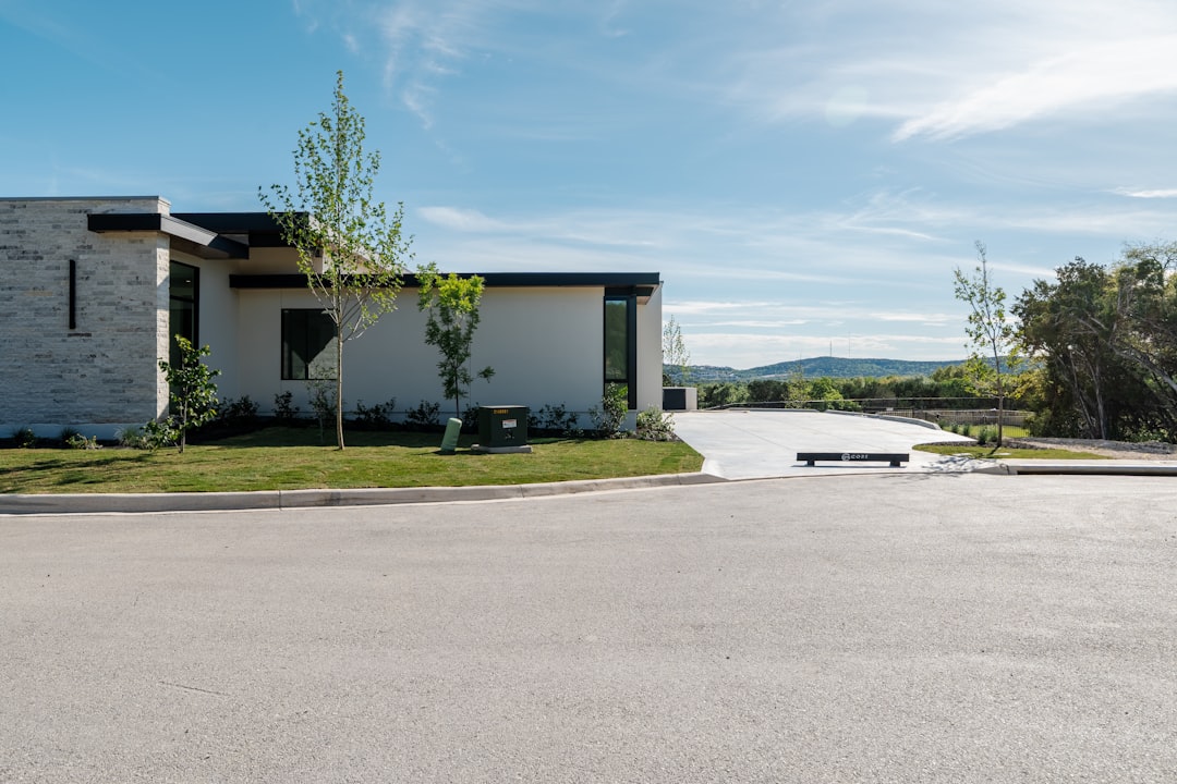 An attractive two-story suburban home with classic architecture and a well-kept front lawn is photographed on a bright, sunny day.