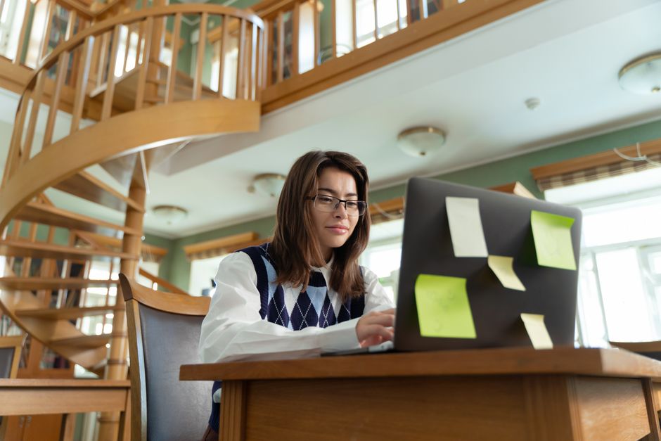 A focused student studies for their real estate license online using a laptop in a bright, modern, and organized home office setting.