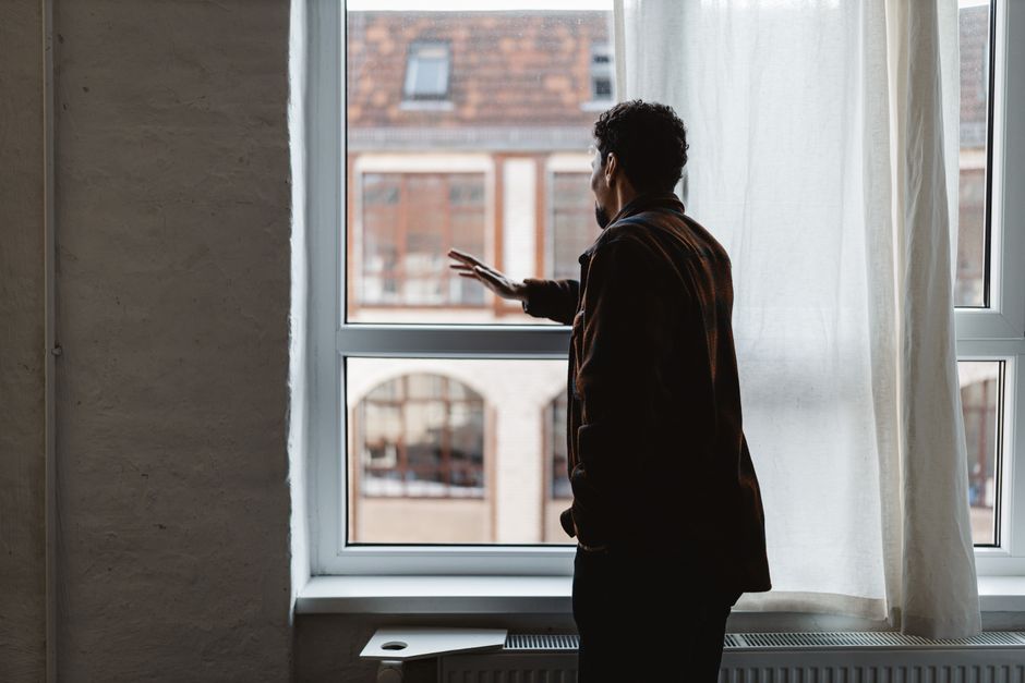 A person stands in a bright, modern office looking out at a cityscape, representing the successful real estate career that starts with a strong educational foundation.