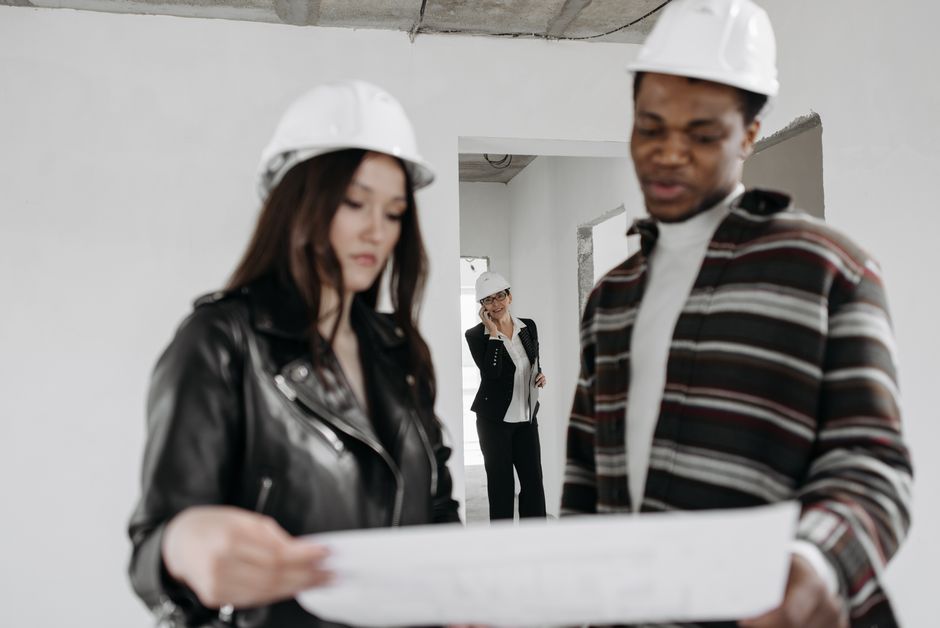 A well-dressed professional thoughtfully examines architectural blueprints, representing the successful career that begins with choosing the right real estate school.