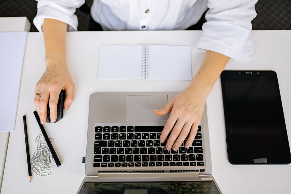 A social worker sits at a bright, clean, and minimalist desk, calmly using a laptop, representing the clarity and organization AI brings to their workflow.